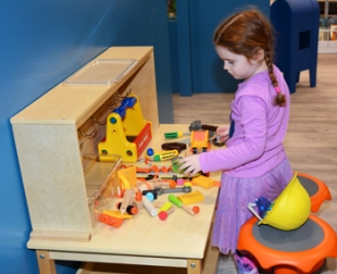 A girl plays at the tool bench station